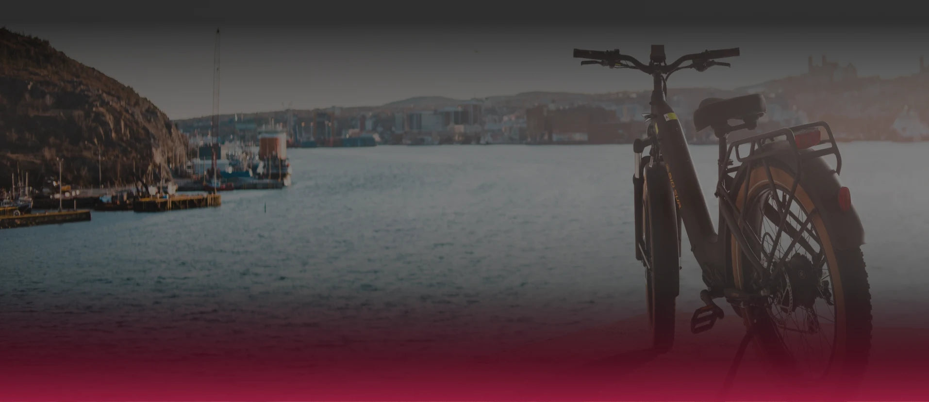 Bicycle parked on a dock with boats and mountains in the background